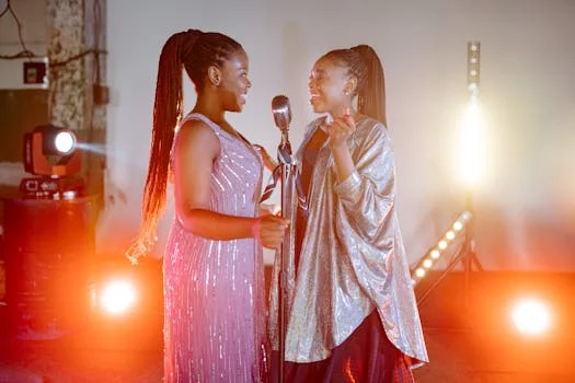 Two talented women singing together on stage with colorful lighting.